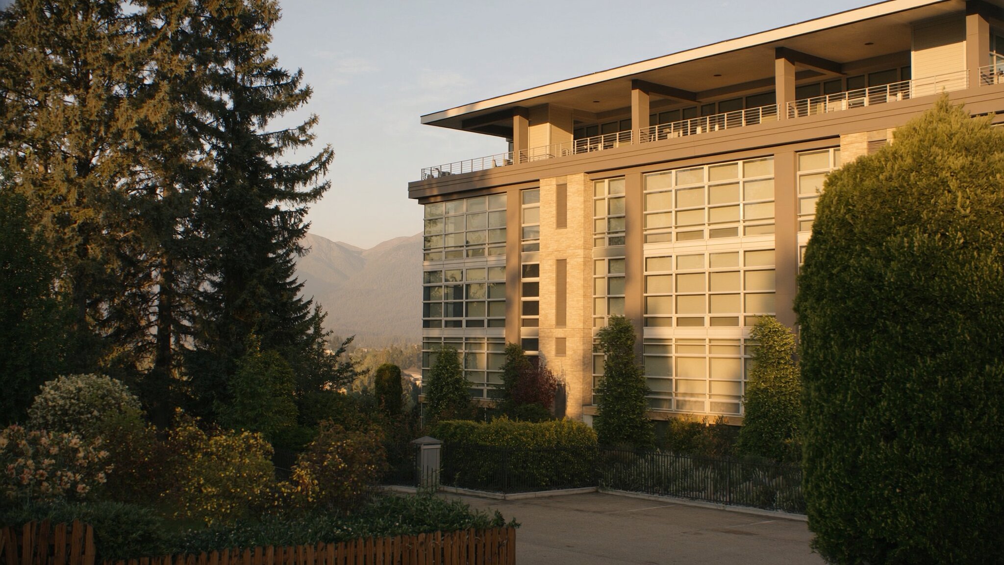 Modern Pacific Northwest condo building exterior with evergreen trees and Cascade Mountain view, King County WA
