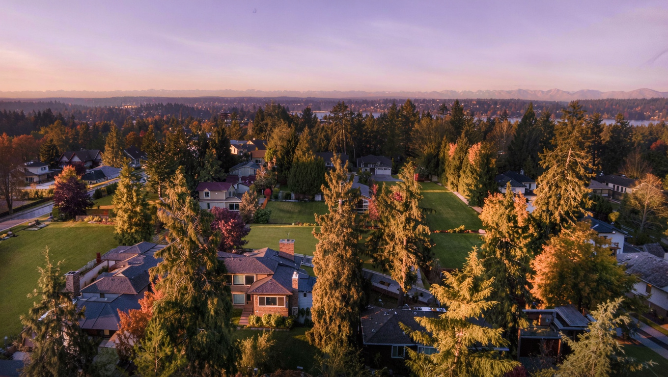 Cinematic golden-hour elevated view of the Aldarra upscale planned community in Sammamish Washington with large custom homes on generous lots, open community green space, and mature Douglas fir and western red cedar throughout the rolling plateau terrain.