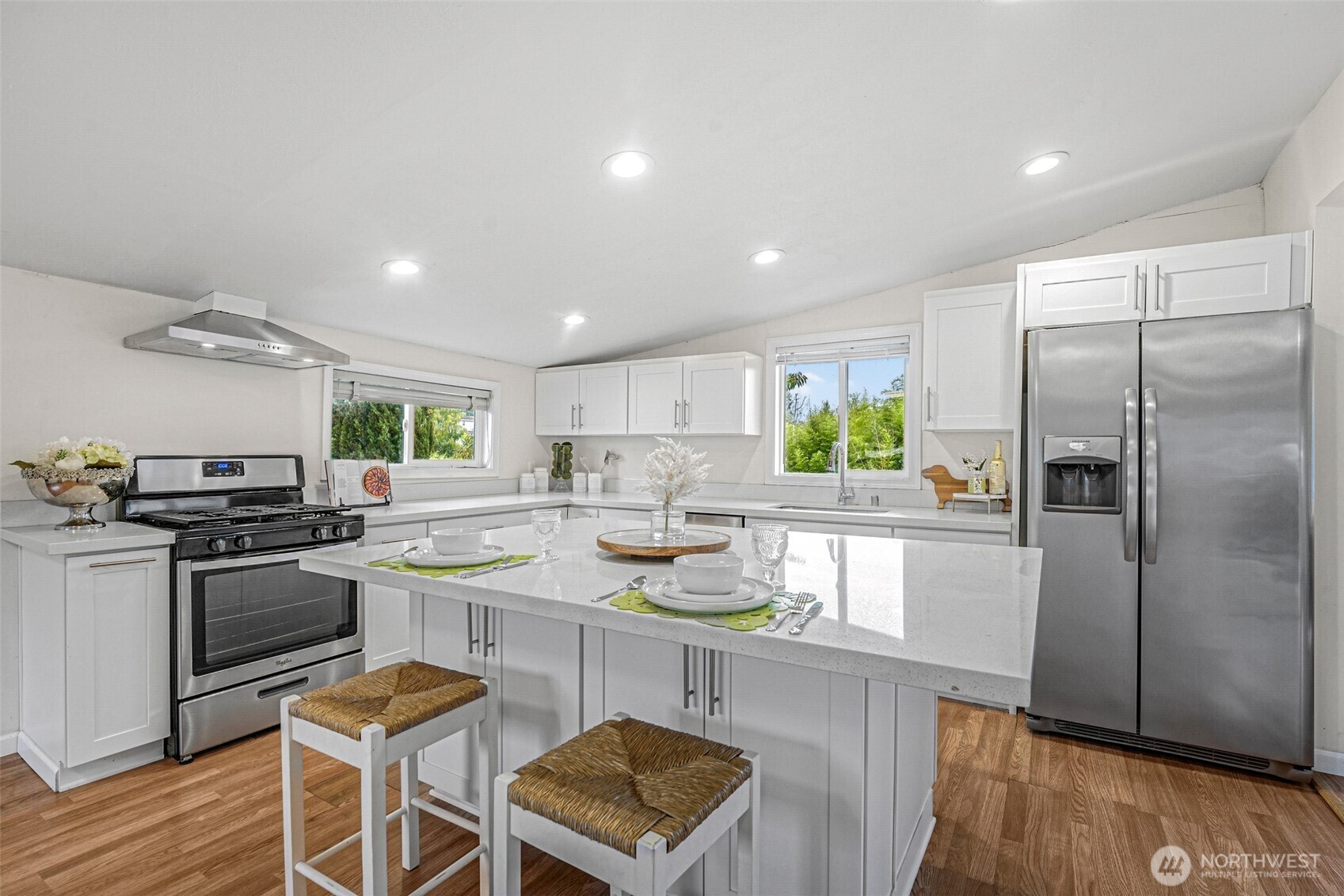 Remodeled kitchen with white cabinets, quartz counters, island seating and stainless appliances
